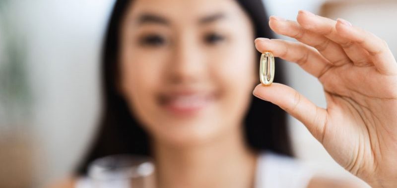 A closeup of supplement pill in a girl hand